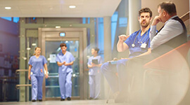 Hospital staff in scrubs walking thru a hospital hallway